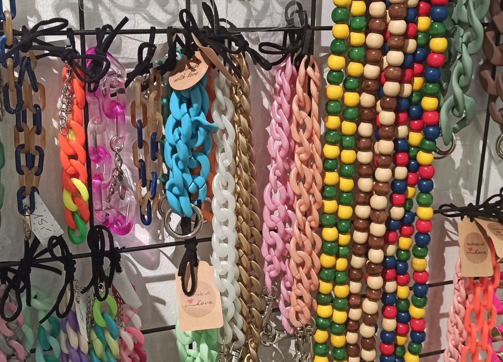 Bunte Ketten und Accessoires an einer Wandaufhängung