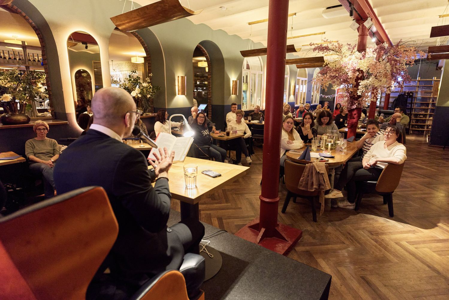 Eine Person im Vordergrund liest vor einem Publikum vor