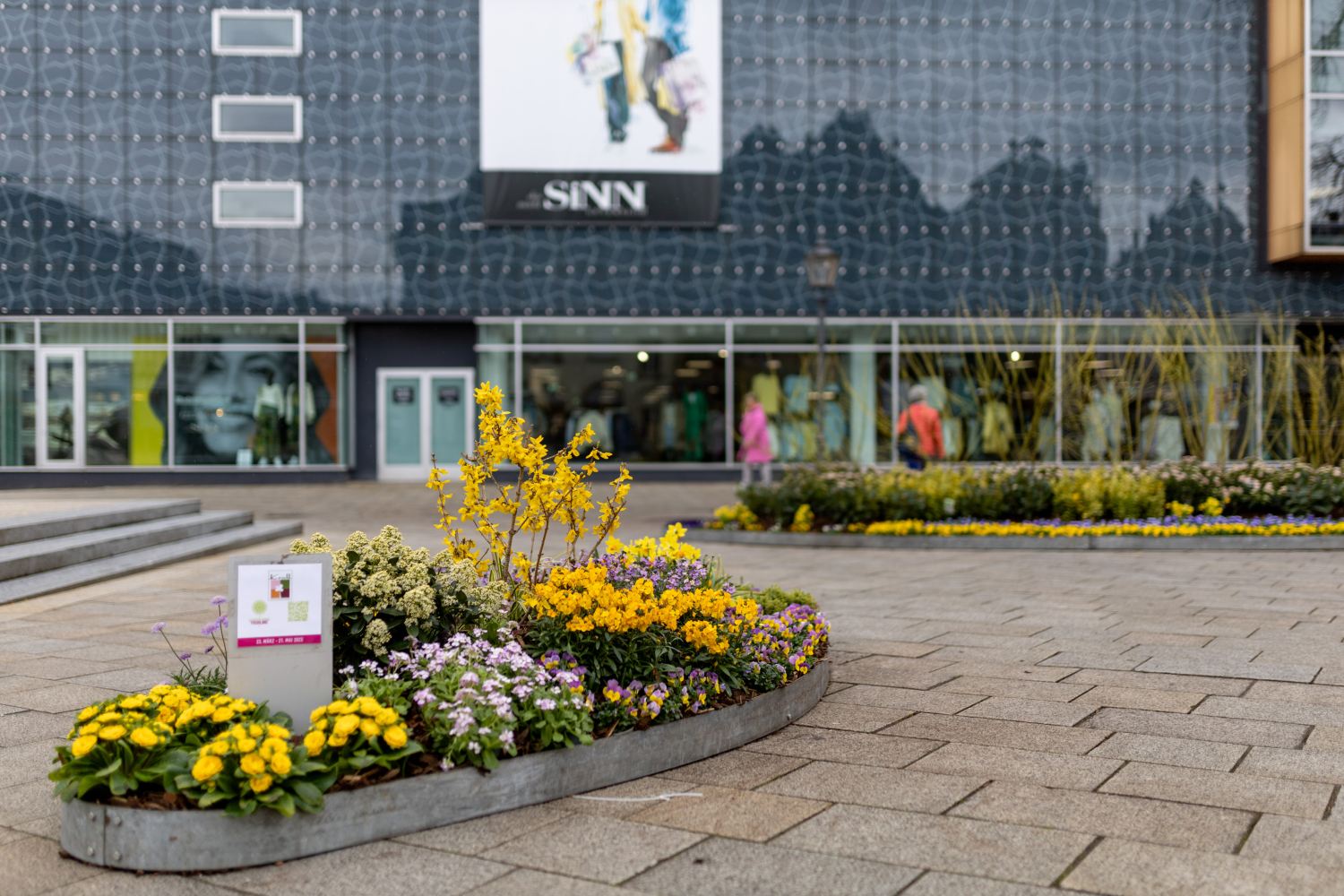 Bepflanzte Ellipsen auf dem Berliner Platz, im Hintergrund das Kaufhaus Sinn